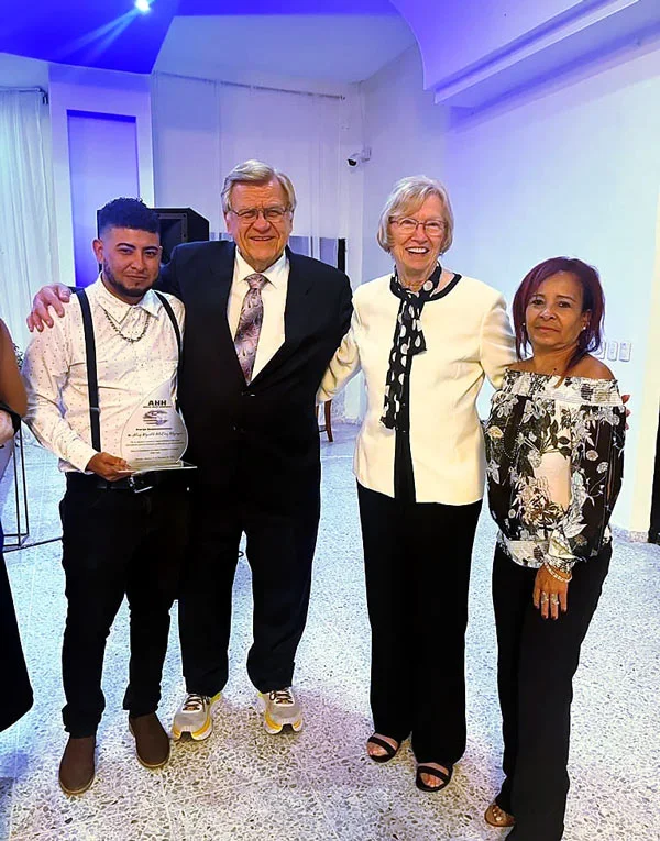 A young man and members of Austin Helps Honduras pose for a group photo at the 2024 annual scholarship banquet.