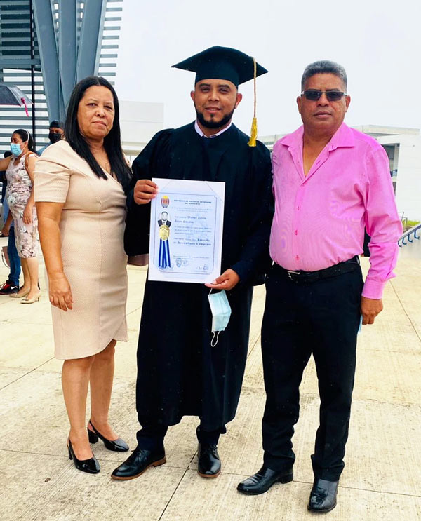 A university student in our scholarship program poses for a photo with their parents at their college's graduation ceremony.