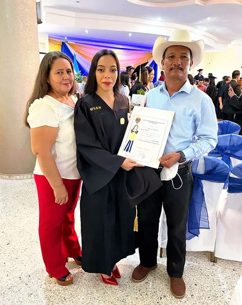 A university student in our scholarship program poses for a photo with their parents at their college's graduation ceremony.