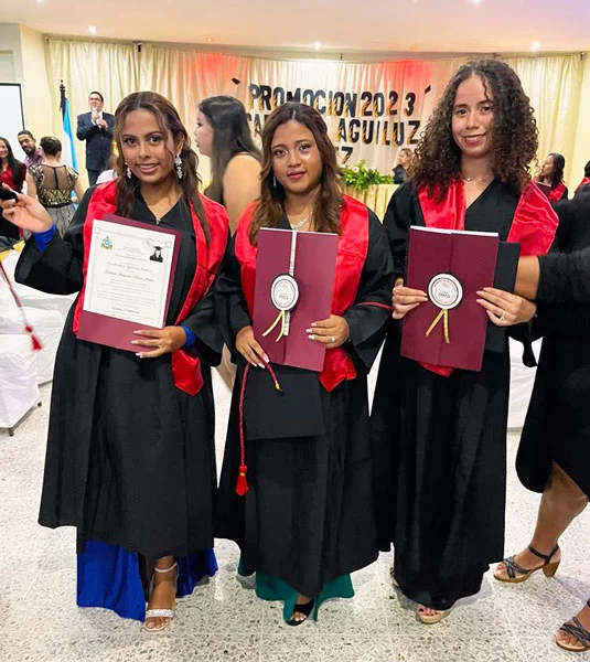 Three vocational students in our scholarship program pose for a photo at their graduation ceremony with their diplomas.