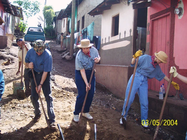 AHH Volunteers shovel dirt along a pathway in town