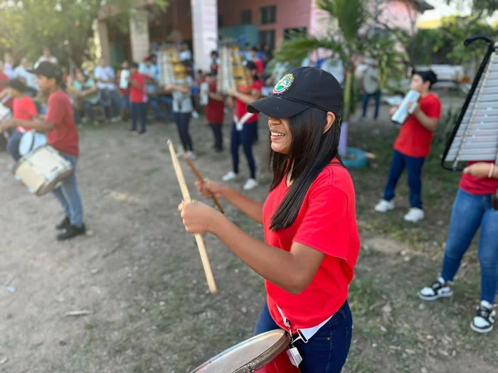 A large group of band students who received donated instruments from AHH practice playing the drums and other musical instruments outside.