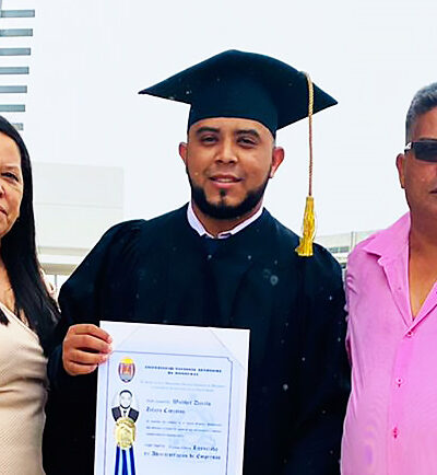 A young man who participated in AHH's scholarship program poses with his parents and his diploma at his college graduation.