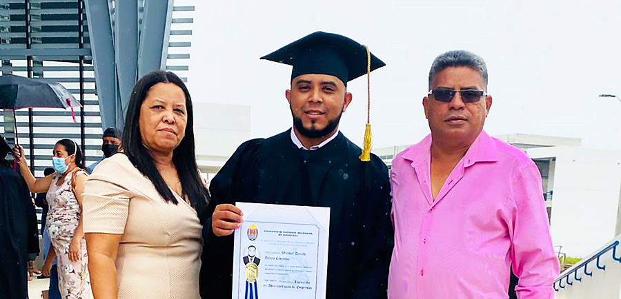 A young man who participated in AHH's scholarship program poses with his parents and his diploma at his college graduation.