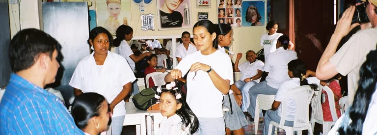 Several children receive haircuts and others wait their turn in a bustling hair salon in Honduras.