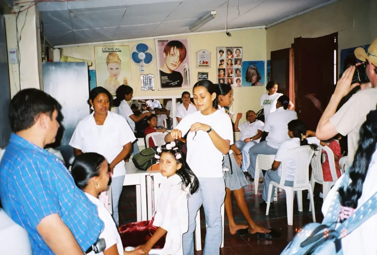 Several children receive haircuts and others wait their turn in a bustling hair salon in Honduras.