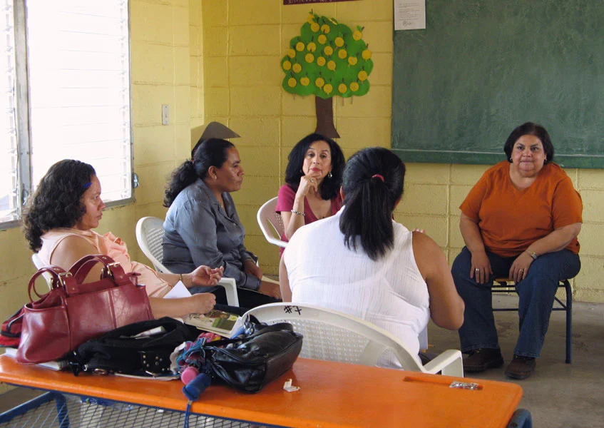 Teachers from the Austin area and local Honduran teachers gather in a group for a teacher training session in an elementary school classroom.