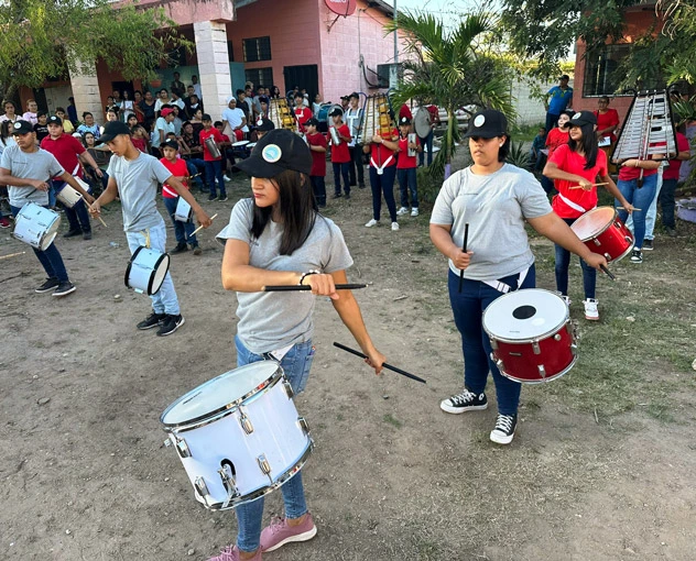 A large group of band students who received donated instruments from Austin Helps Honduras practice playing the drums and other musical instruments outside.